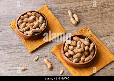 Immagine di un mazzo di arachidi in una ciotola su un tavolo di legno Foto Stock