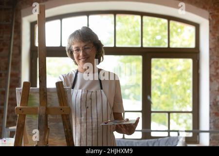 Felice anziano donna in pensione godendo hobby creativo in studio d'arte Foto Stock