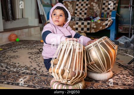 un bambino piccolo che cerca di imparare a giocare il tabla . Foto Stock