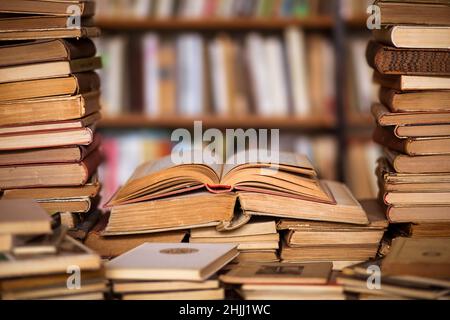 Vecchi libri sul tavolo nella libreria antiquaria - libri aperti, pagine di libri, libreria sfocata sullo sfondo Foto Stock