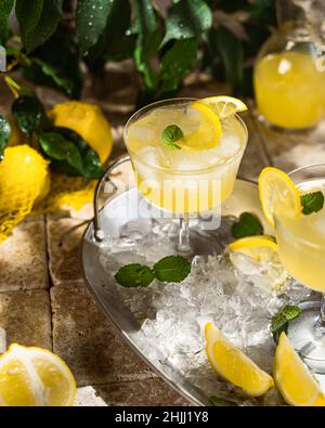 Limoncello digestivo tipico italiano con limoni freschi e ghiaccio, fuoco selettivo Foto Stock