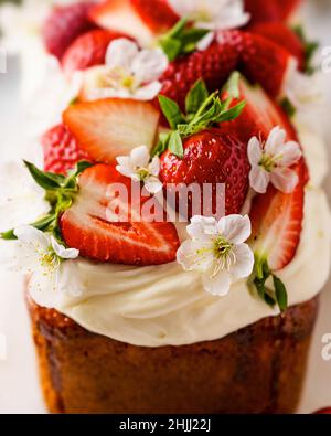 Torta estiva con fragole e formaggio cremoso su tavola di marmo bianco. Dessert estivo fatto in casa con decorazioni primaverili. Idee per il brunch. Dessert pasquale. Foto Stock