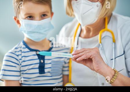 Medico pediatra che esamina i capretti piccoli nel test covid clinico Foto Stock