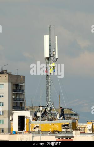 Gli ingegneri installano nuove antenne di telecomunicazione per la tecnologia 5G su un tetto residenziale a Sofia, Bulgaria Foto Stock