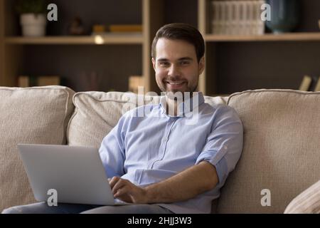 Ritratto di bel giovane uomo che usa il computer a casa. Foto Stock