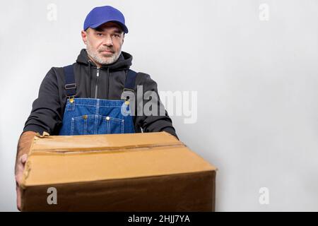 Ritratto di un uomo in tuta con scatola di cartone. Uomo Bluecollar Foto Stock