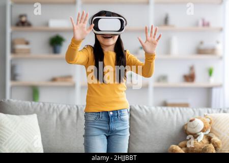 Ragazza allegra adolescente con occhiali VR, toccando qualcosa di invisibile Foto Stock