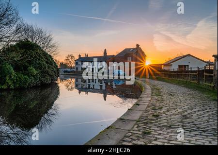 Prestolee, Bolton, UK Weather, 30th gennaio 2022. La calma tra Storm Malik e Storm Corrie è catturata in acque perfettamente ferme mentre l'alba illumina i ciottoli del Manchester, Bolton e Bury Canal costruito nel 1808 che si snoda attraverso il paesaggio urbano del nord di Manchester. Credit: Tom McATEE/Alamy Live News Foto Stock