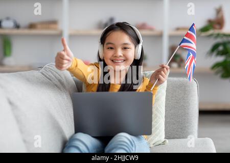 Ragazza adolescente cinese felice usando il laptop, imparando la lingua straniera in linea Foto Stock