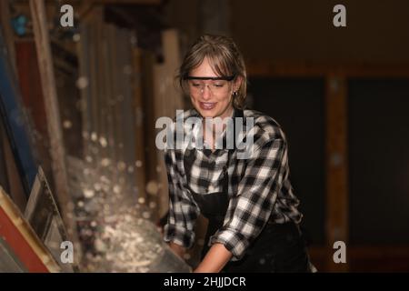 Felice giovane donna lavora in un laboratorio di legno. Concetto di femminismo Foto Stock