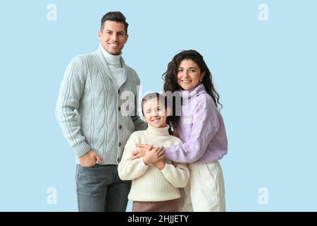 Bambina e i suoi genitori in maglioni caldi su sfondo chiaro Foto Stock