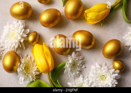 Uova di Pasqua dipinte d'oro e fiori su sfondo chiaro Foto Stock