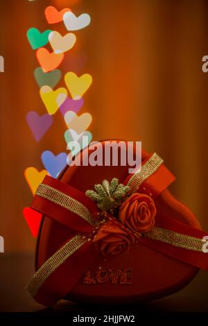 Una romantica scena di una scatola a forma di cuore di cioccolatini con un  bouquet di rose rosse Foto stock - Alamy