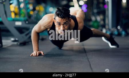 Motivato giovane sportivo arabo fare esercizio push up su una mano Foto Stock