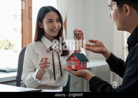 Agente immobiliare sta spiegando lo stile della casa ai clienti che vengono a contatto per vedere il disegno della casa e l'accordo di acquisto Foto Stock