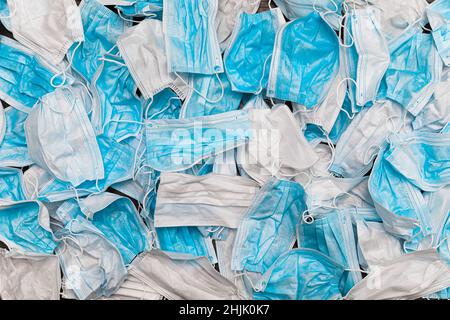 Maschere mediche usate. Pila di dispositivi di protezione individuale DPI usati. Inquinamento maschere chirurgiche durante la pandemia di coronavirus. Grande numero di medici usati Foto Stock