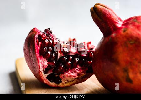 Primo piano di un segmento di melograno e melograno su un tagliere di legno Foto Stock