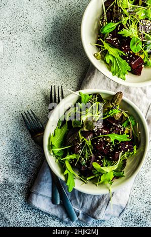 Vista dall'alto di due ciotole di barbabietola grigliata con insalata mista a foglie e semi di sesamo Foto Stock