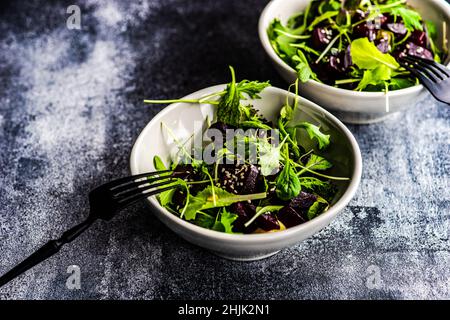 Vista dall'alto di due ciotole di barbabietola grigliata con insalata mista a foglie e semi di sesamo Foto Stock