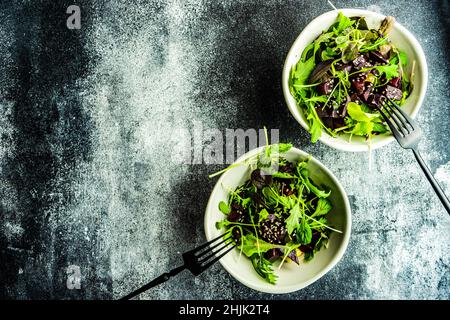 Vista dall'alto di due ciotole di barbabietola grigliata con insalata mista a foglie e semi di sesamo Foto Stock