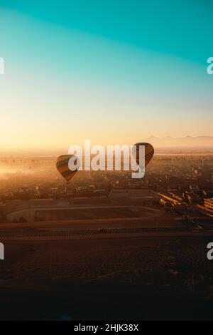 Luxor Egitto Gennaio 2021 colpo verticale di due mongolfiere ad aria calda a luxor, egitto. Incredibile alba di prima mattina illuminata sopra le incredibili terre nebbia Foto Stock