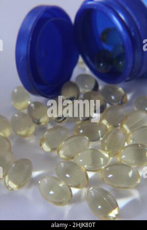 Bottiglia blu di capsule di vitamina omega 3 olio di pesce con qualche fuoriuscita sul primo piano bianco Foto Stock