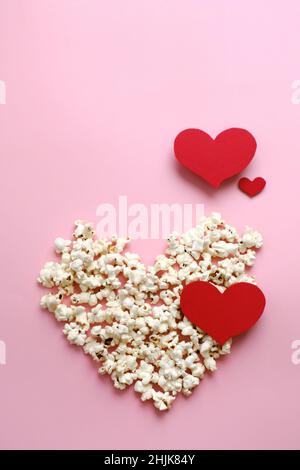 Pop Corn cuore su sfondo rosa. Il giorno di San Valentino presenta il concetto di cinema. Vista dall'alto, disposizione piatta con spazio per la copia. Luogo per idea, citazione o titolo del film Foto Stock