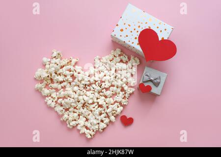 Pop Corn cuore su sfondo rosa. Biglietto giornaliero per San Valentino per il cinema. Vista dall'alto, disposizione piatta con spazio per la copia. Confezioni regalo, festa d'amore Foto Stock