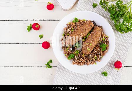 Cena sana. Recipiente per il pranzo con porridge di grano saraceno, cotolette di carne al forno e melanzane arrostite. Vista dall'alto, sopra Foto Stock