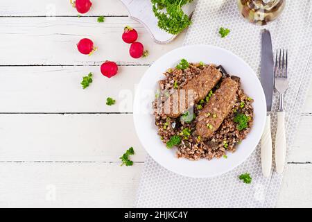 Cena sana. Recipiente per il pranzo con porridge di grano saraceno, cotolette di carne al forno e melanzane arrostite. Vista dall'alto, sopra Foto Stock
