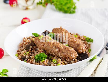 Cena sana. Recipiente per il pranzo con porridge di grano saraceno, cotolette di carne al forno e melanzane arrostite. Foto Stock