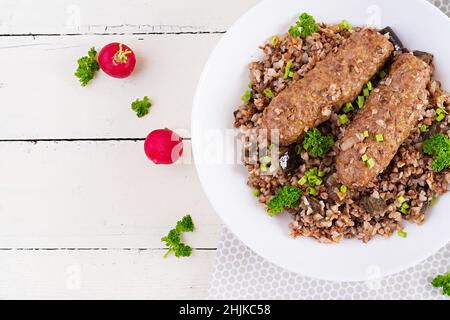 Cena sana. Recipiente per il pranzo con porridge di grano saraceno, cotolette di carne al forno e melanzane arrostite. Vista dall'alto, sopra Foto Stock