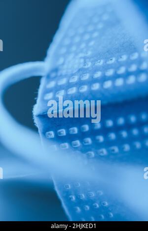 Composizione creativa astratta della maschera chirurgica in colori ultramarini profondi posti su una superficie riflettente. Foto Stock