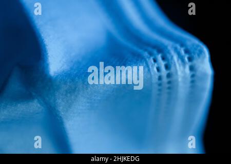 Maschera chirurgica in toni ultramarini profondi su sfondo scuro - macro shoot Foto Stock