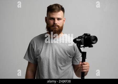 Videografo professionista che utilizza la fotocamera dslr su stabilizzatore gimbal isolato su sfondo bianco. Foto Stock