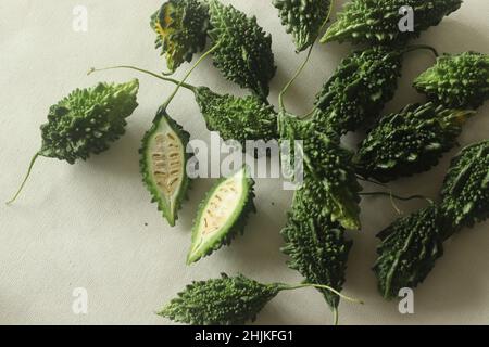 La zucca amara, nota anche come pavakka o karela, è una vite tropicale che appartiene alla famiglia delle zucche dal gusto amaro. Ripresa su sfondo bianco con evidenziazione Foto Stock