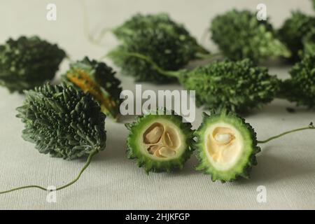 La zucca amara, nota anche come pavakka o karela, è una vite tropicale che appartiene alla famiglia delle zucche dal gusto amaro. Ripresa su sfondo bianco con evidenziazione Foto Stock