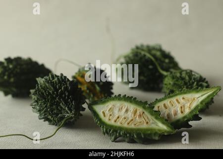 La zucca amara, nota anche come pavakka o karela, è una vite tropicale che appartiene alla famiglia delle zucche dal gusto amaro. Ripresa su sfondo bianco con evidenziazione Foto Stock