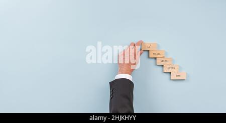 Immagine concettuale del successo e della visione di affari - mano di un uomo d'affari che fa i punti di legno pioli che leggono i piccoli punti giorno evergy. Foto Stock