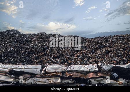 Un cumulo di veicoli in un deposito di rottami da frantumare e vendere per i materiali Foto Stock