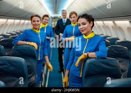 Lavoratori aerei che si trovano in cabina passeggeri dell'aeroplano Foto Stock