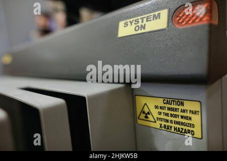 Dettagli della profondità di campo poco profonda (messa a fuoco selettiva) con il messaggio di attenzione su una macchina scanner per bagagli a raggi X. Foto Stock