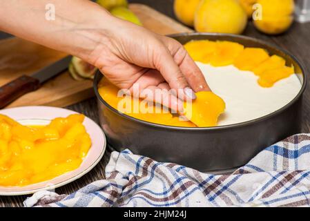 Cottura della cheesecake. Il cuoco decora la cheesecake con frutta a fette. Donna decora cheesecake. Foto Stock