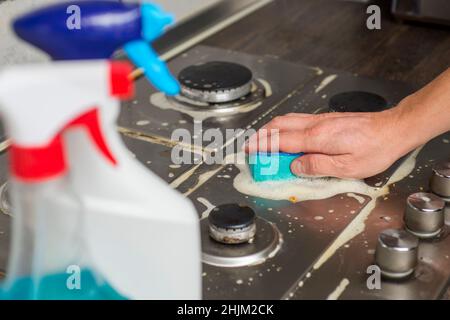 Fornello a gas per pulizia manuale con spugna e detersivi. Pulizia di una stufa a gas con utensili da cucina, concetti di casa, o igiene e pulizia. Foto Stock