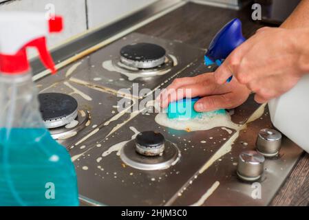 Fornello a gas per pulizia manuale con spugna e detersivi. Pulizia di una stufa a gas con utensili da cucina, concetti di casa, o igiene e pulizia. Foto Stock