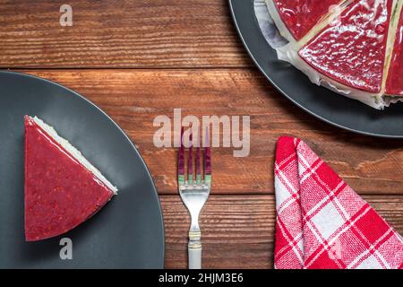 Classica cheesecake con gelatina di lamponi su sfondo rustico tavolo in legno, vista dall'alto. Foto Stock