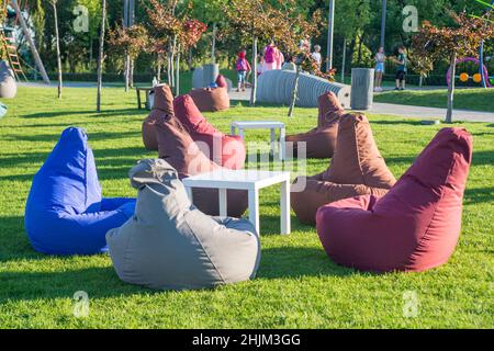 Molti sedili colorati in sacchi di fagioli per rilassarsi sull'erba all'aperto. Un luogo conveniente per rilassarsi, una compagnia o per uno. Foto Stock