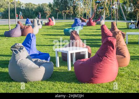 Molti sedili colorati in sacchi di fagioli per rilassarsi sull'erba all'aperto. Un luogo conveniente per rilassarsi, una compagnia o per uno. Foto Stock