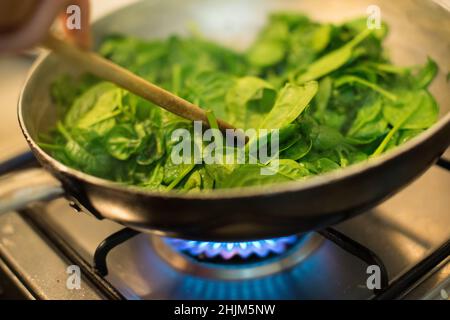 Spinaci in una pentola con fuoco acceso Foto Stock