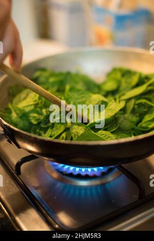 Spinaci in una pentola con fuoco acceso Foto Stock